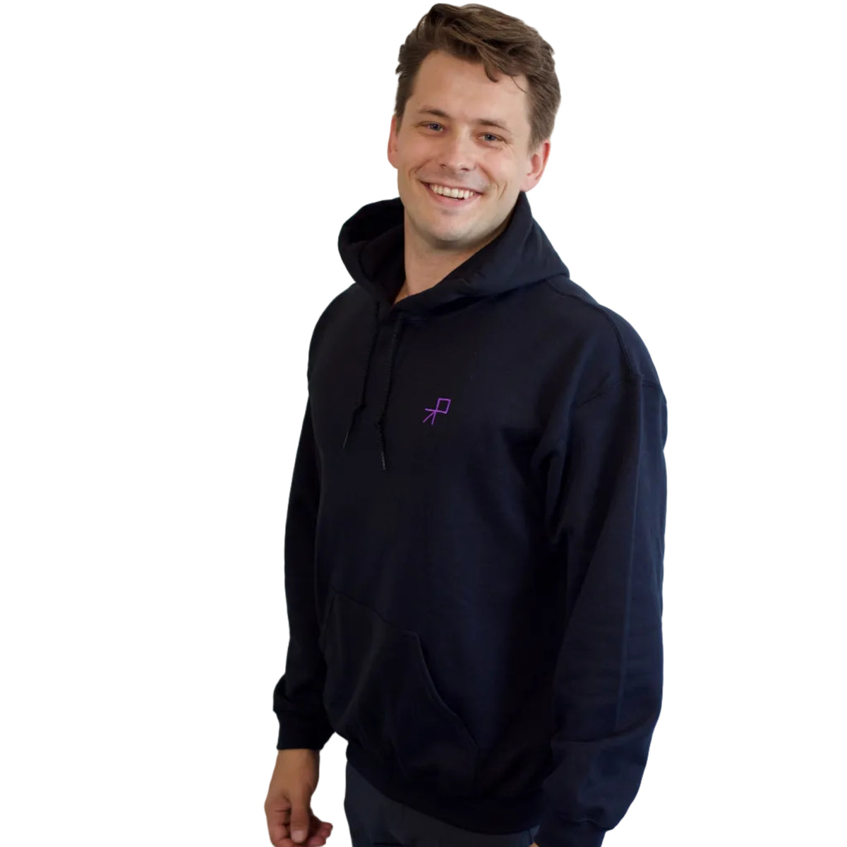 A man wearing a black hoodie with a small purple embroidered push logo on the left chest, photographed against a solid white background. His left shoulder is closer to the camera than his right. 