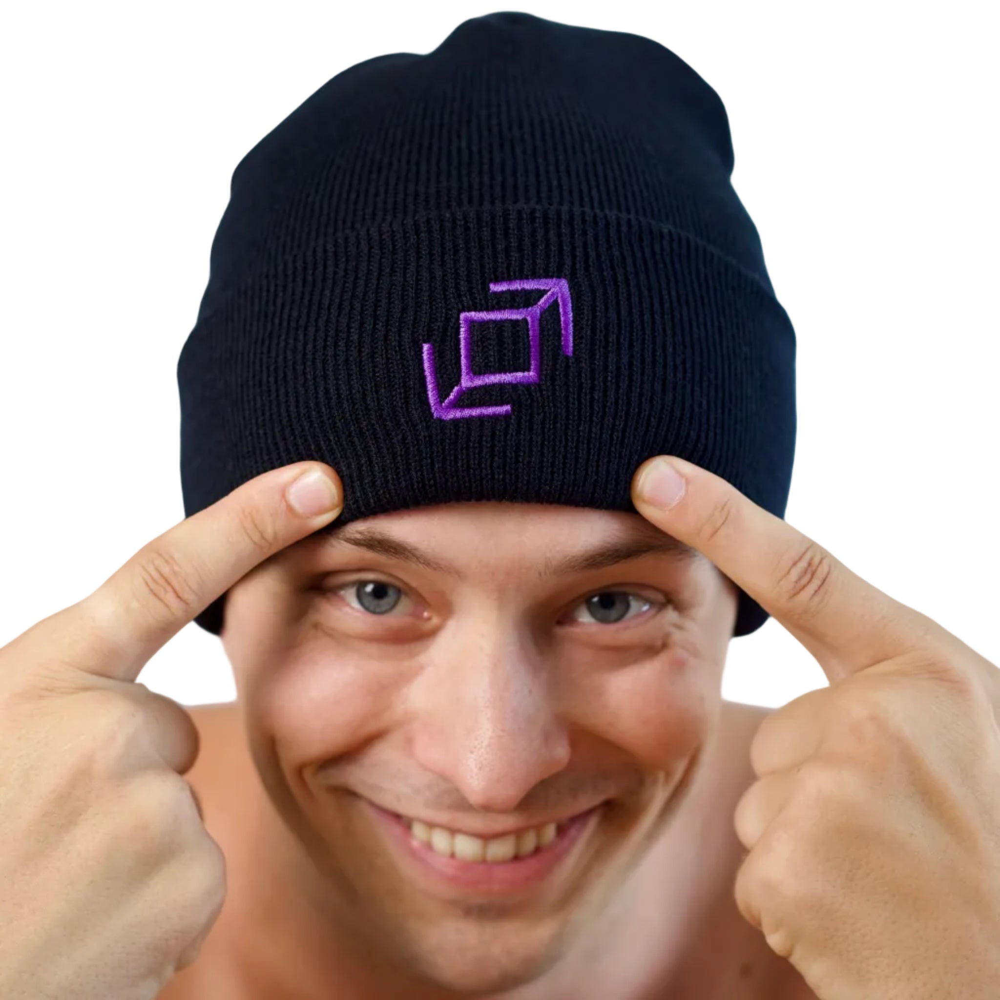 A close-up of a smiling dancer wearing a black knit push pass whip beanie with a purple geometric whip logo embroidered on the front, pointing at his head against a light blue background.