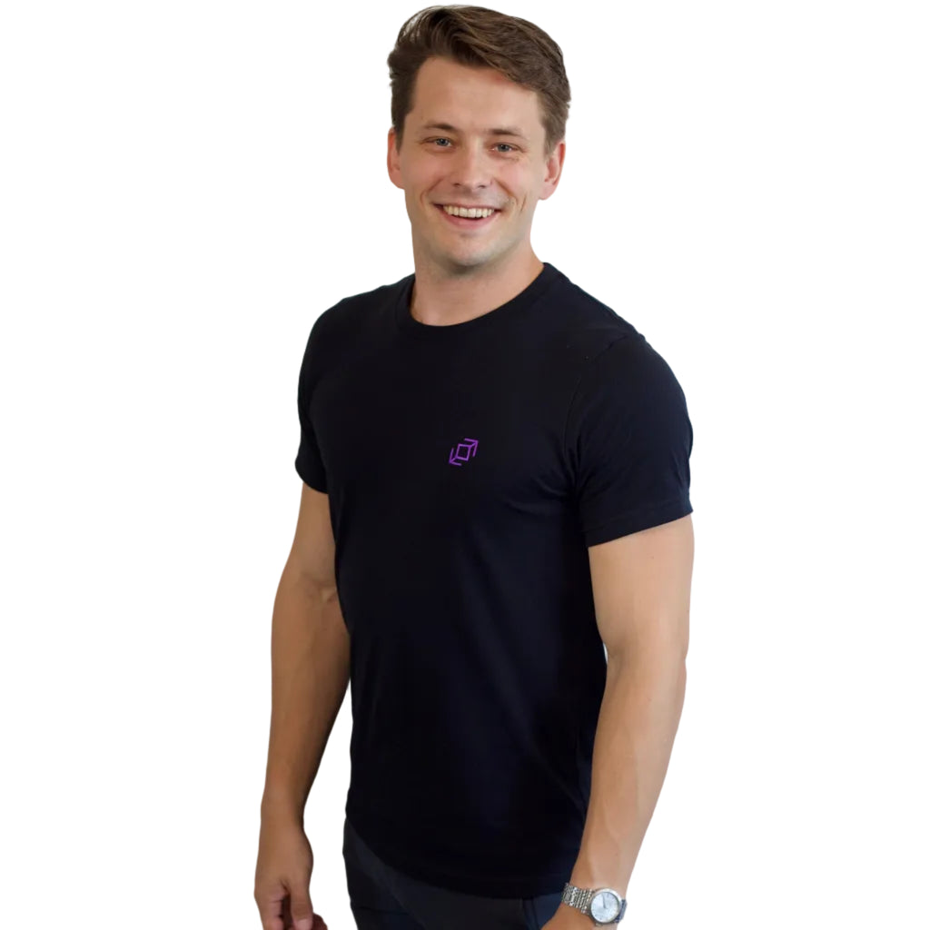 Dancer standing with a side view of a black PPW Push tee showing the embroidered whip icon at chest height